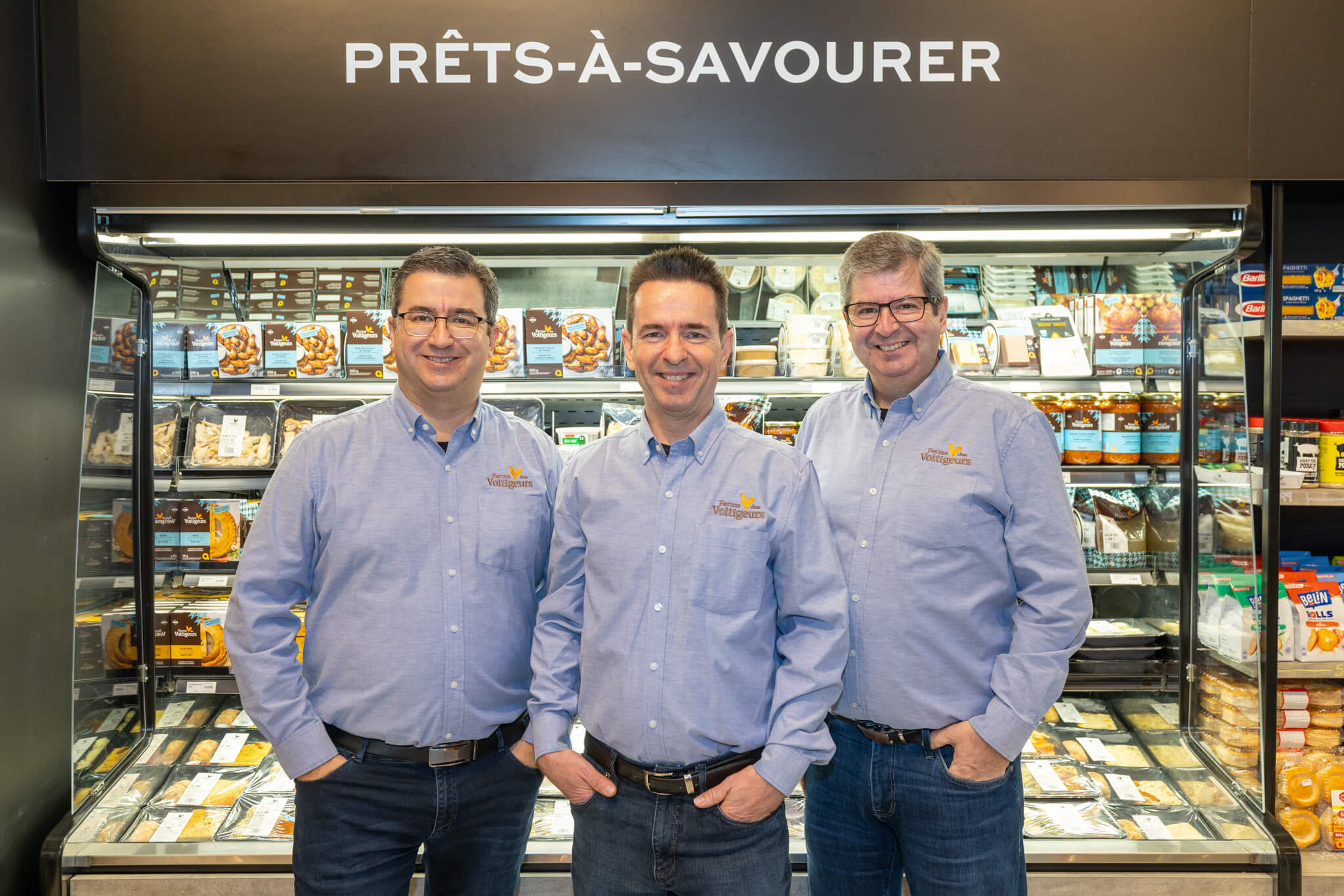 L'équipe de Ferme des Voltigeurs prend la pose devant un réfrigérateur rempli de ses produits.