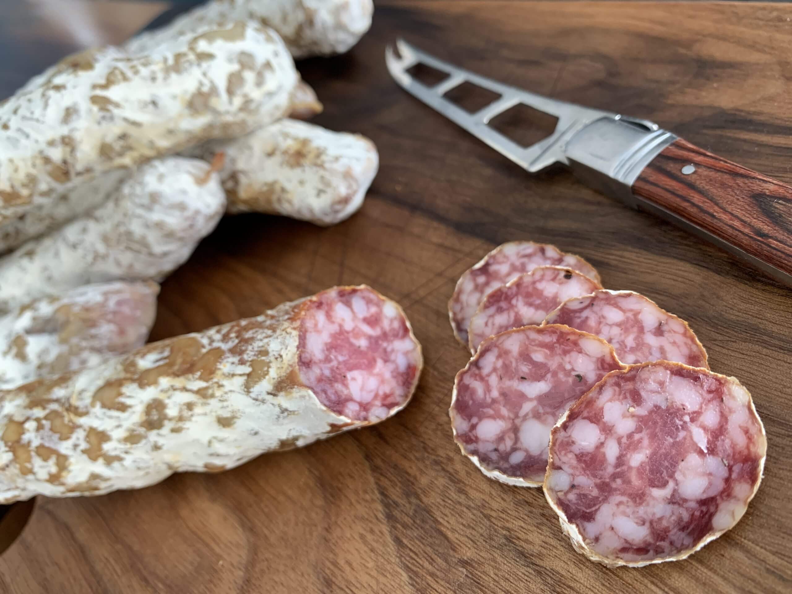 Des saucissons secs de Les Pendules, coupés sur une planche de bois.