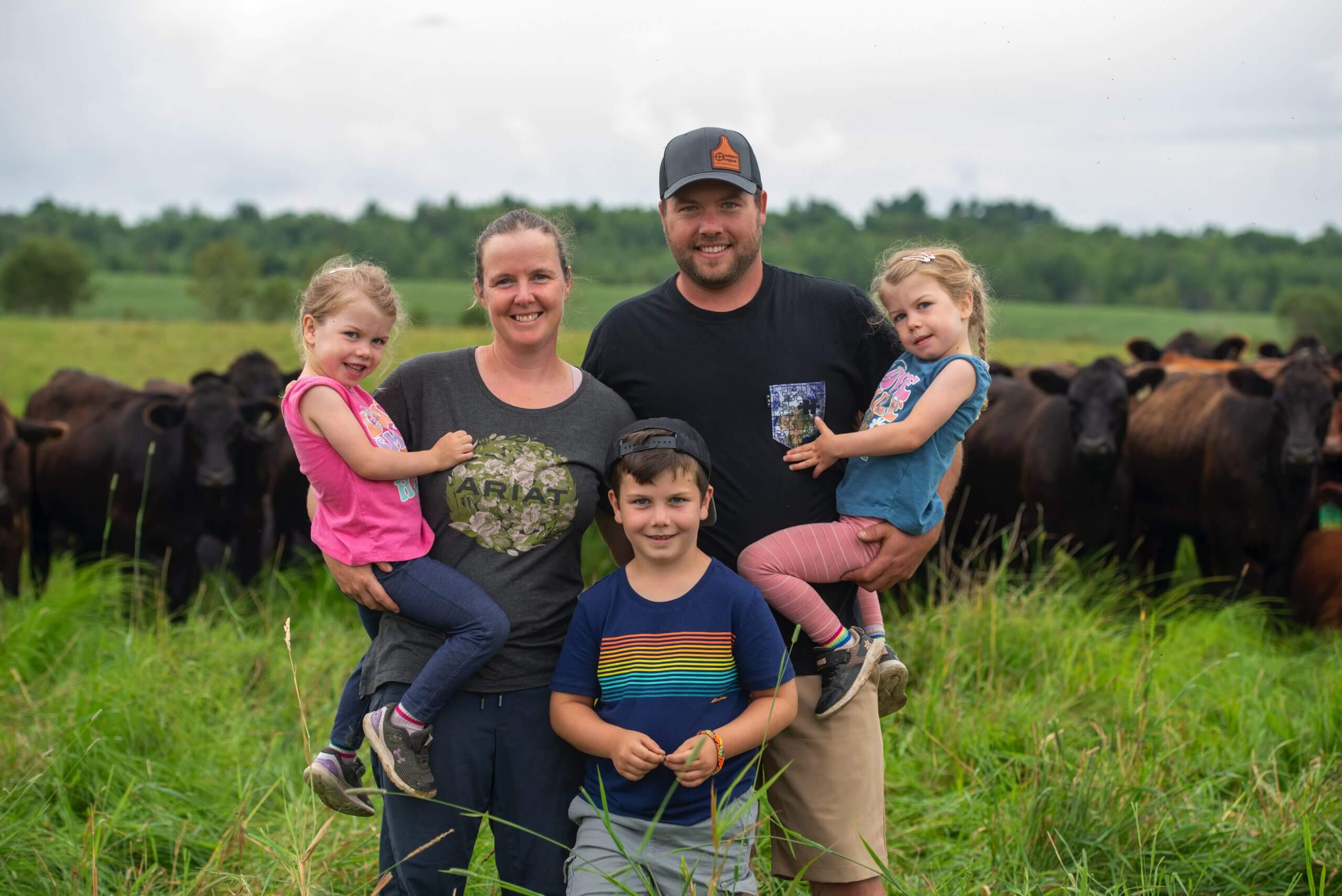 Les propriétaires de Paysan Gourmand et leurs enfants dans un champs devant des boeufs.