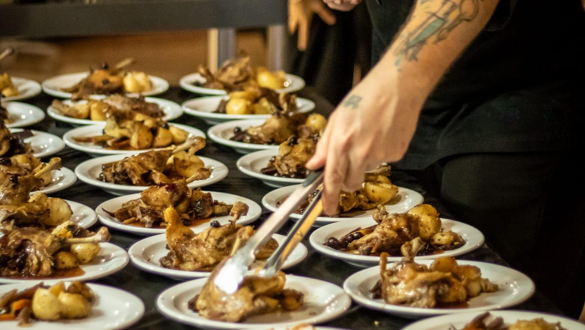 La main d'un chef de Midigo Presto préparant de nombreuses assiettes de repas de volaille.