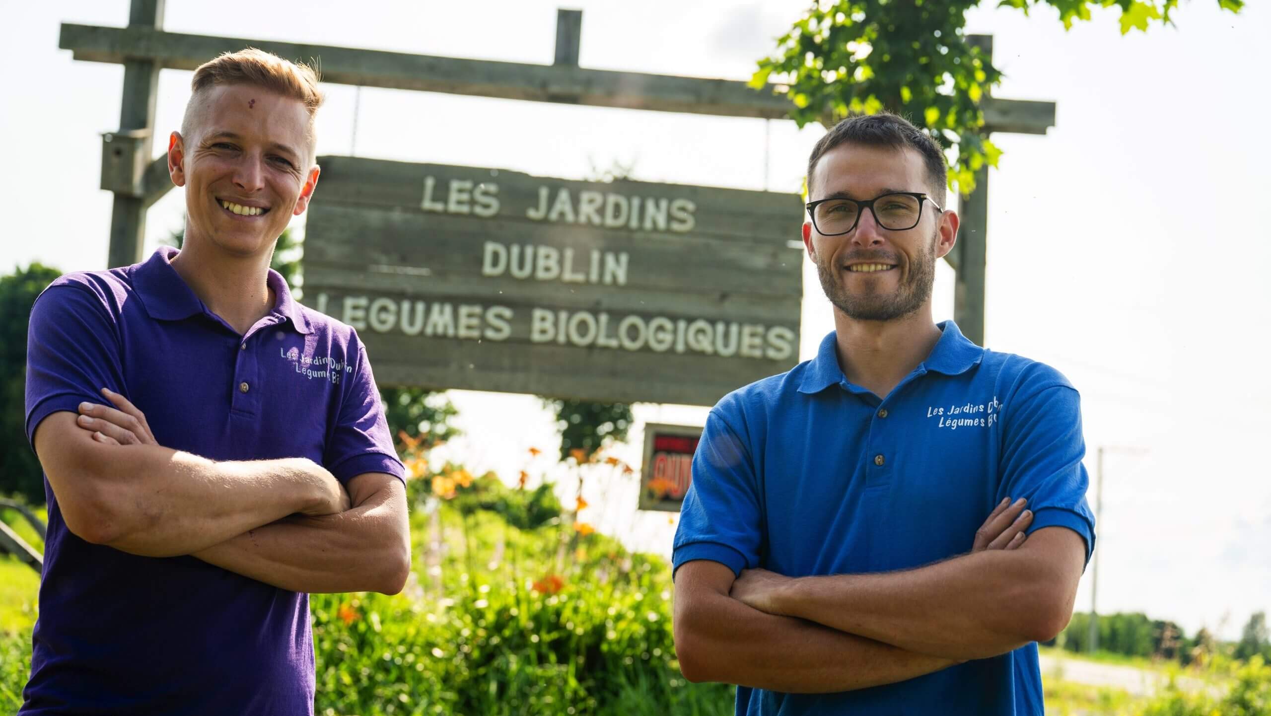 Les deux propriétaires des Jardins Dublin prenant la pose devant l'enseigne de la ferme.