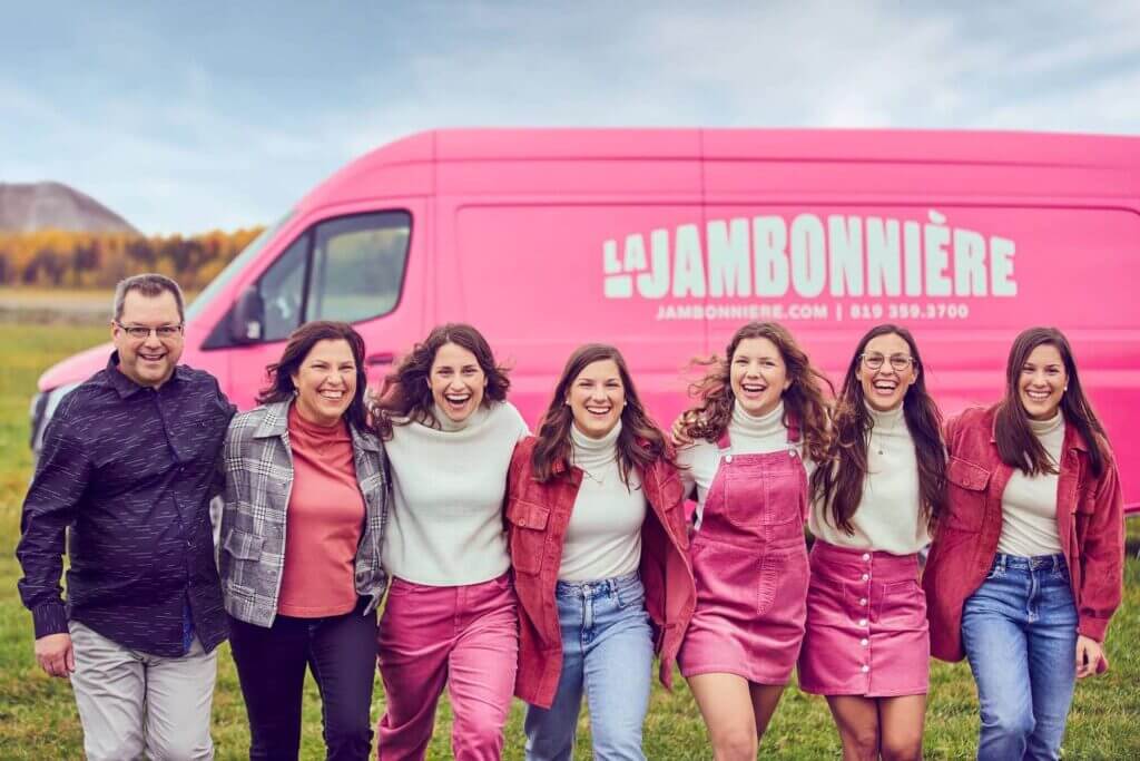 La famille derrière La Jambonnière posant bras dessus, bras dessous devant leur camionnette de livraison.